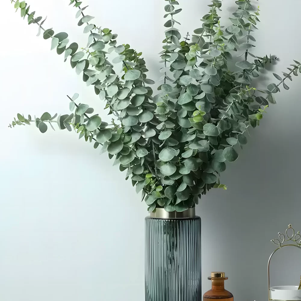 The artificial green eucalyptus stem arranged in a transparent glass vase. The minimalist design adds a touch of elegance to any interior setting, enhancing modern or rustic decor styles.