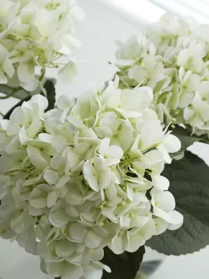 A close-up image capturing the fine details of the white artificial hydrangea petals, showcasing the lifelike texture and delicate layering that mimics real flowers with remarkable accuracy.