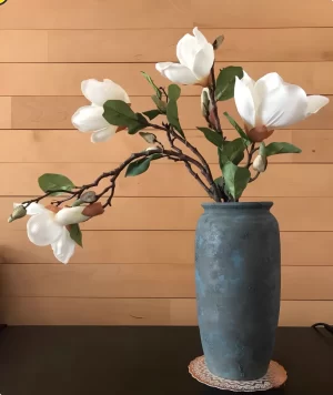 Set against a cozy home background, these artificial magnolias in a stylish blue ceramic vase add a touch of elegance and sophistication to any interior. The lifelike petals and vibrant leaves create a natural, fresh look that lasts all year long.