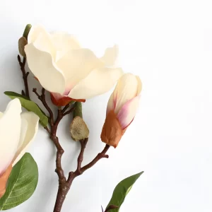 The close-up captures the delicate and lifelike petals of the artificial magnolia flower, showing off its realistic texture and soft, natural color. A perfect choice for those seeking high-quality faux floral arrangements.