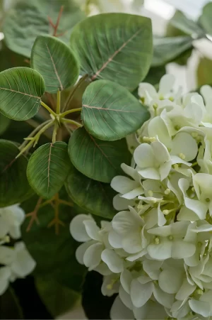 A close-up view of the faux hydrangea petals and leaves showcases the intricate design and craftsmanship. The realistic texture of the petals and the detailed leaf veins create an authentic botanical look for any decor.