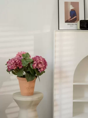 Set on a luxurious marble table, this large pink hydrangea arrangement brings elegance and color to any space. The floral piece is accompanied by a beautiful artwork backdrop, enhancing the sophisticated ambiance of the room.