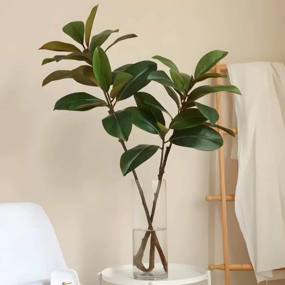 A lifestyle scene showing two magnolia leaf stems elegantly placed in a glass vase, adding a touch of nature to the home decor.