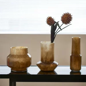 The trio of amber vases arranged on the dining table brings warmth and life to the home, with each vase adding its own character to the harmonious, vibrant setting.