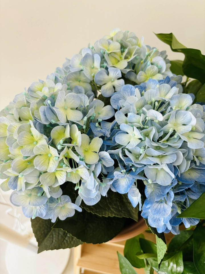 A stunning close-up of the blue artificial hydrangea, showcasing the intricate details of each petal and the vibrant yellow stamens at the center. This shot captures the realism of the petals, giving you a sense of the quality and lifelike appearance of the product. Perfect for adding a touch of elegance to any space.