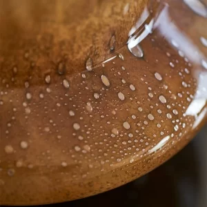 A close-up of the cone-shaped vase's base reveals hand-crafted details like subtle bubbles, black-and-white specks, and flow lines, showcasing its artisanal quality and vintage-inspired texture.