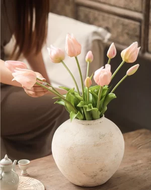 This ceramic vase, paired with soft pink faux tulips, brings a romantic and gentle vibe to any room. The rounded shape and textured ceramic finish balance beautifully with the tulips’ softness, making it a perfect accent piece for a warm, inviting atmosphere.