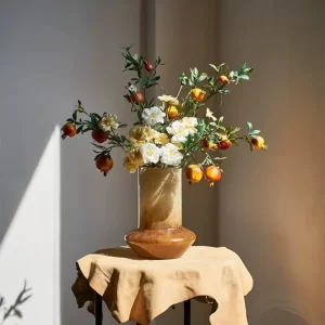 This charming display pairs the amber glass cone-shaped vase with faux pomegranate and delicate flowers, creating an eye-catching and cozy arrangement that brings a touch of nature indoors.