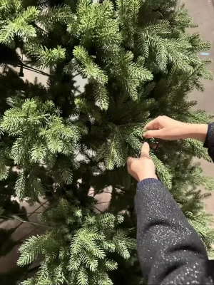 Here, the homeowner is making final adjustments to the beautifully decorated Christmas tree. Carefully spreading the branches creates a natural and full appearance, ready for holiday festivities.