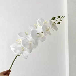 A close-up view of a single artificial white orchid stem, showcasing its graceful design and lifelike details. Perfect for standalone display or pairing with other stems to create a captivating arrangement.