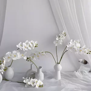 A unique variation of white orchids arranged in elegant white vases, showcasing their versatility in home styling. These premium artificial flowers bring a touch of serenity and sophistication to any setting.