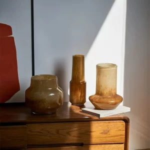 These amber vases sit elegantly on a desk, illuminated by warm afternoon sunlight. Their earthy tones add a soothing and natural vibe to the workspace.